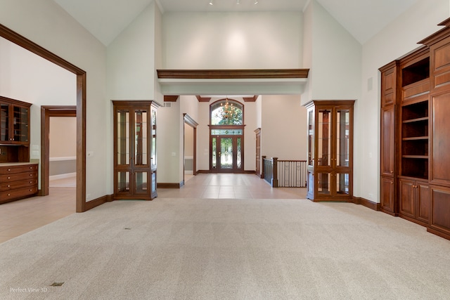 entryway with light colored carpet and high vaulted ceiling