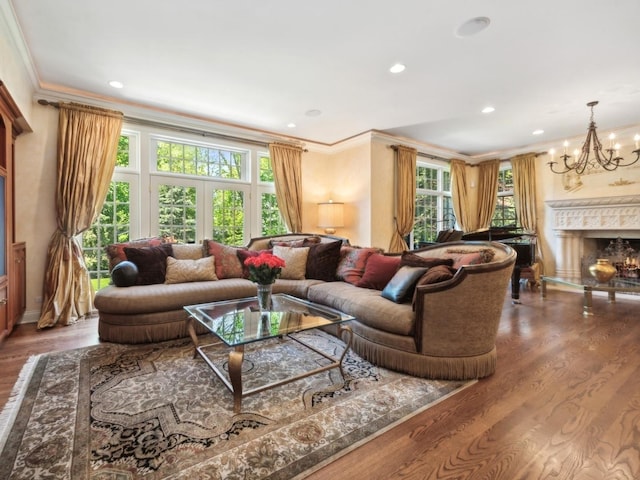 living area featuring recessed lighting, wood finished floors, a high end fireplace, ornamental molding, and an inviting chandelier