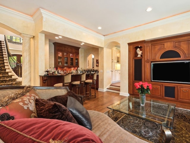 living room featuring arched walkways, indoor bar, stairway, and wood finished floors