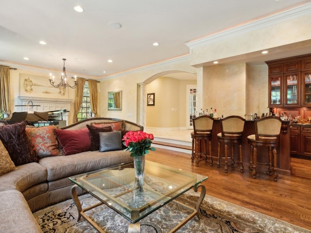 living room with arched walkways, recessed lighting, bar, wood finished floors, and ornate columns