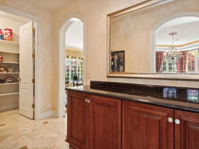 bar with arched walkways, a notable chandelier, hanging light fixtures, and light tile patterned floors