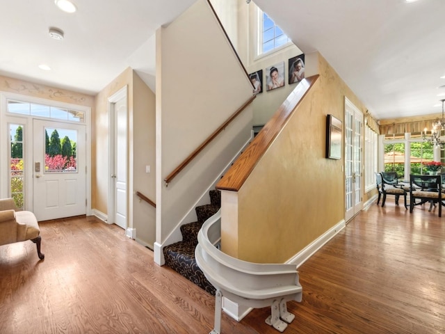 foyer with recessed lighting, a notable chandelier, wood finished floors, baseboards, and stairway