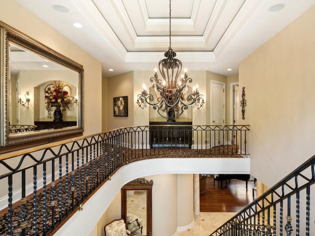 stairway with recessed lighting, ornamental molding, a raised ceiling, and a chandelier