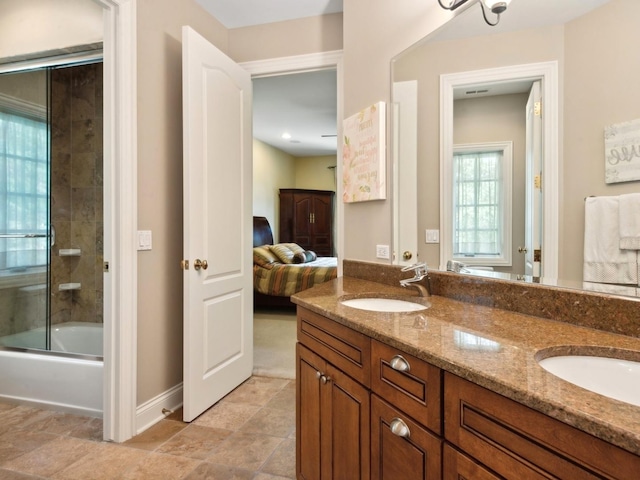 ensuite bathroom featuring double vanity, connected bathroom, combined bath / shower with glass door, and a sink