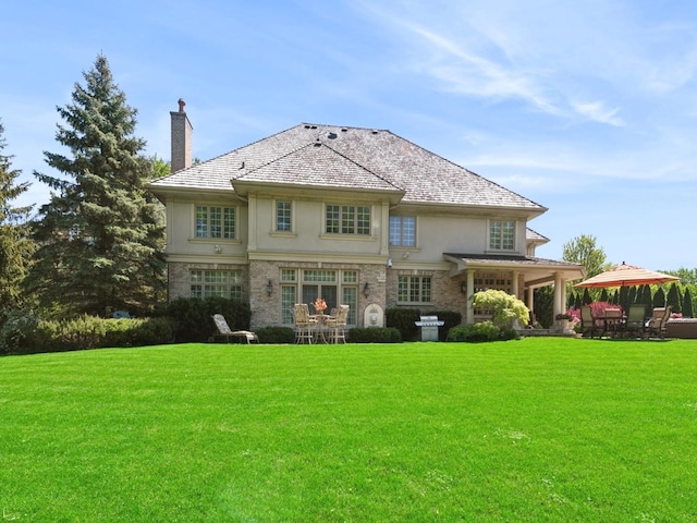 rear view of property featuring a yard, a chimney, a gazebo, and stucco siding