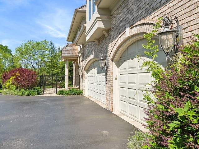 garage with aphalt driveway, fence, and a gate