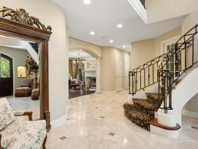 foyer featuring arched walkways, a warm lit fireplace, recessed lighting, and baseboards