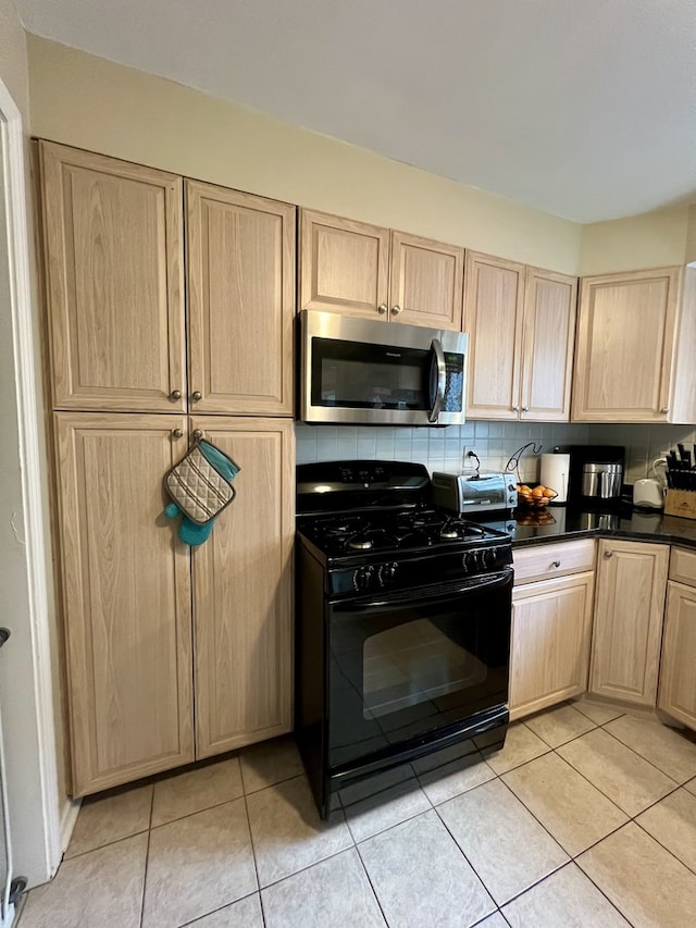 kitchen with black gas range, decorative backsplash, light brown cabinets, and light tile patterned floors