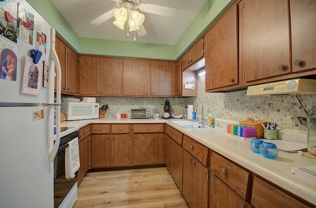 kitchen with backsplash, white appliances, ceiling fan, sink, and light hardwood / wood-style flooring