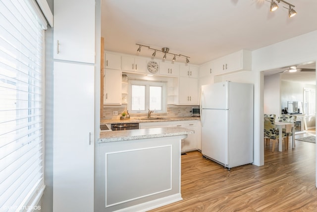 kitchen with tasteful backsplash, light hardwood / wood-style floors, sink, white cabinets, and white fridge