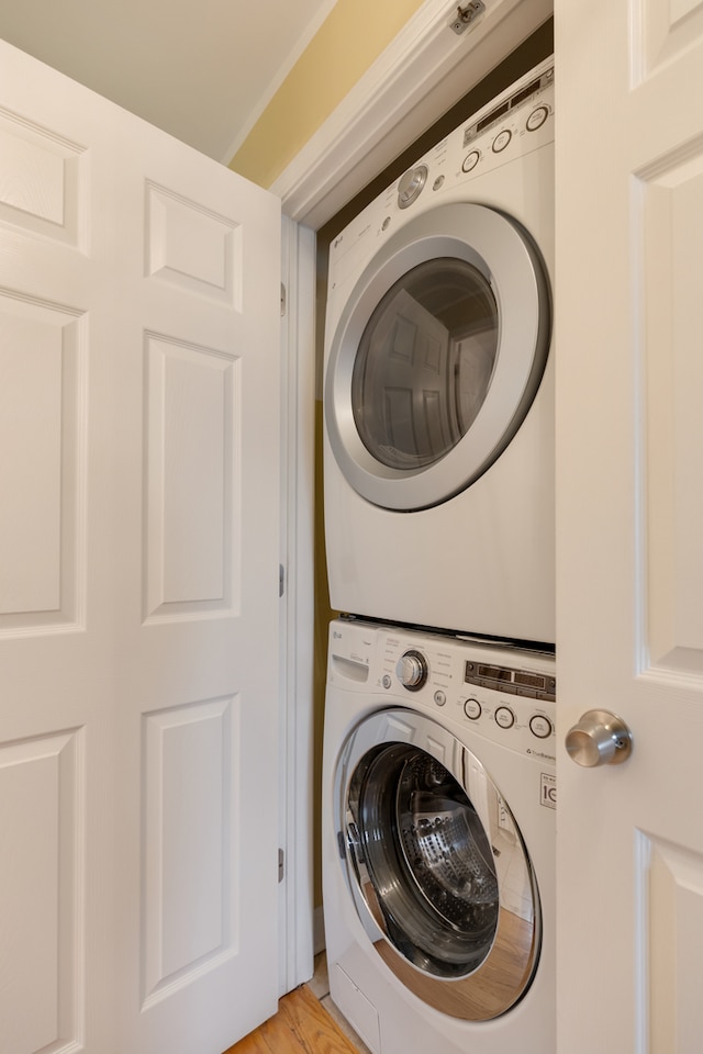 laundry room featuring light hardwood / wood-style floors and stacked washer and clothes dryer