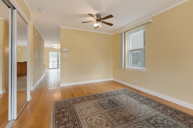 empty room featuring crown molding, light hardwood / wood-style flooring, and ceiling fan with notable chandelier