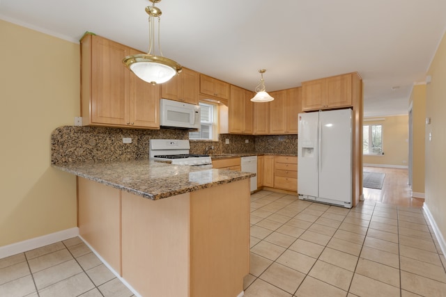 kitchen featuring backsplash, white appliances, hanging light fixtures, and a wealth of natural light