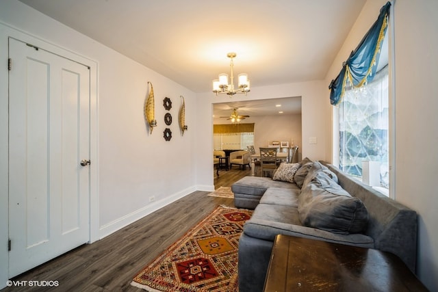 living room featuring a wealth of natural light, dark wood-type flooring, and ceiling fan with notable chandelier