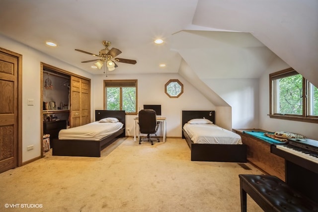 carpeted bedroom with a closet, multiple windows, lofted ceiling, and ceiling fan