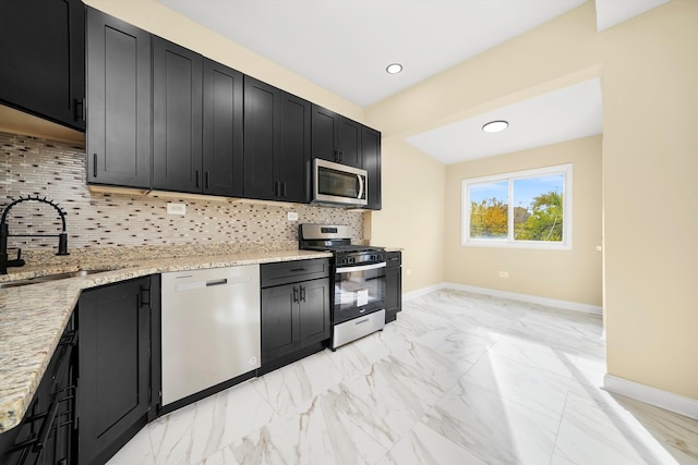 kitchen with stainless steel appliances, light stone counters, tasteful backsplash, and sink