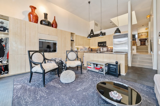 interior space featuring hanging light fixtures, stainless steel built in fridge, a towering ceiling, decorative backsplash, and light brown cabinetry