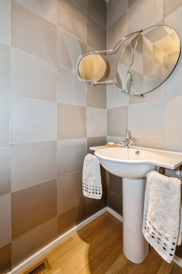 bathroom with wood-type flooring and tile walls