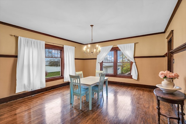 dining area featuring dark hardwood / wood-style flooring, crown molding, and a notable chandelier