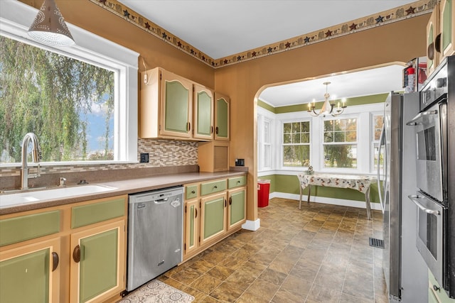 kitchen with decorative backsplash, stainless steel appliances, sink, pendant lighting, and a chandelier