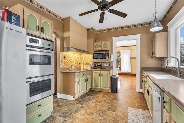 kitchen featuring backsplash, hanging light fixtures, sink, ceiling fan, and appliances with stainless steel finishes