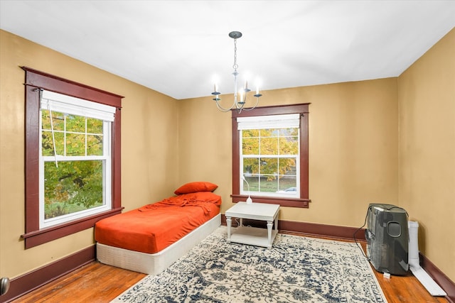 bedroom featuring hardwood / wood-style flooring, multiple windows, and a notable chandelier