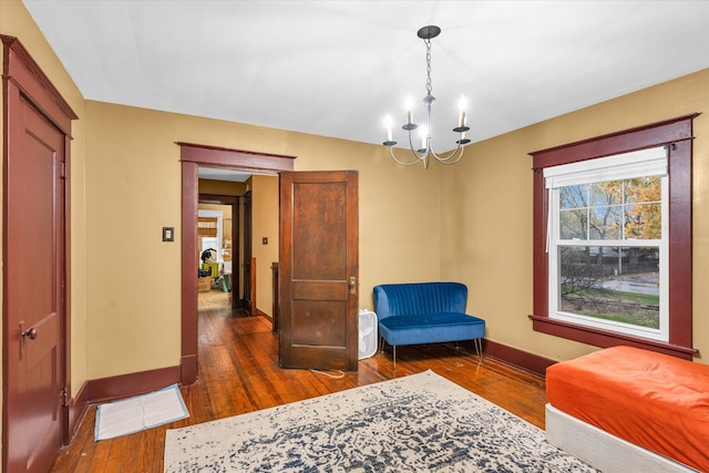 sitting room featuring dark wood-type flooring and an inviting chandelier