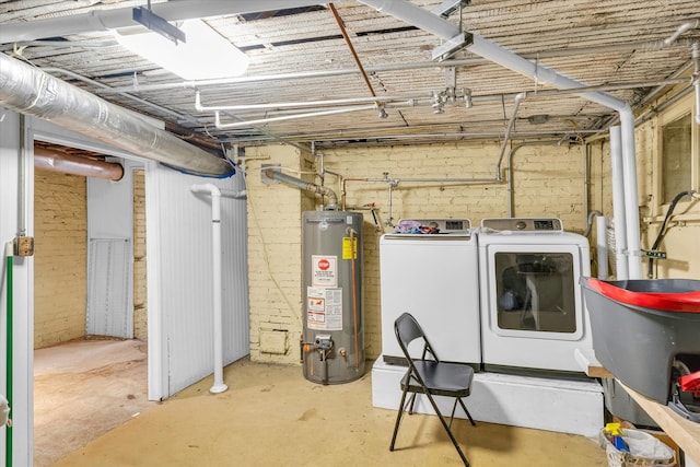 basement featuring brick wall, washer and dryer, and gas water heater