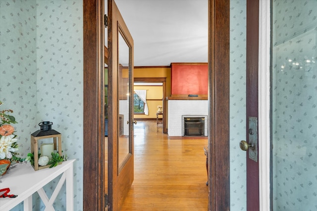 hall with light wood-type flooring and crown molding