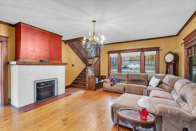 living room with an inviting chandelier, light hardwood / wood-style floors, a brick fireplace, and ornamental molding