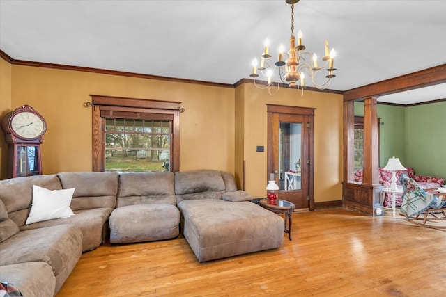 living room with decorative columns, crown molding, light hardwood / wood-style floors, and a notable chandelier