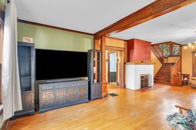 living room with wood-type flooring, crown molding, and a notable chandelier