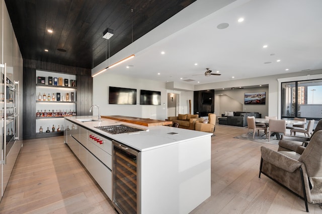 kitchen featuring a spacious island, sink, white cabinets, light hardwood / wood-style floors, and wine cooler