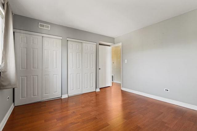 unfurnished bedroom with multiple closets and hardwood / wood-style floors