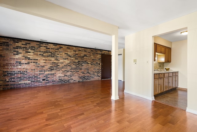 unfurnished living room featuring dark hardwood / wood-style flooring and brick wall