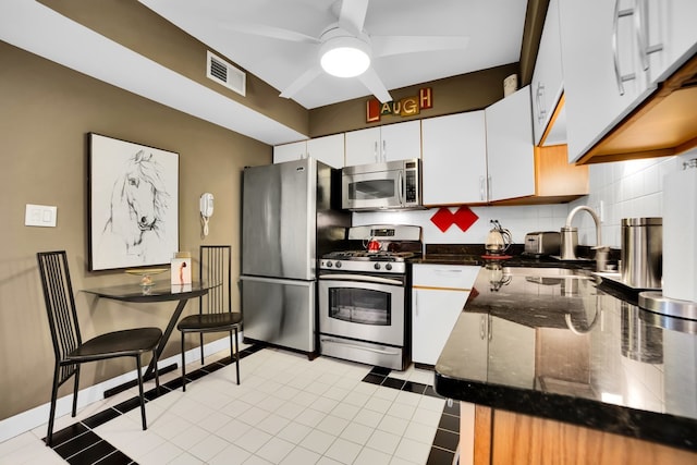 kitchen with backsplash, sink, light tile patterned floors, white cabinetry, and stainless steel appliances