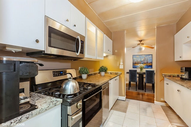 kitchen with ceiling fan, stainless steel appliances, light stone counters, and white cabinetry