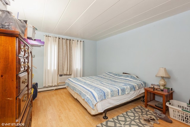 bedroom featuring a baseboard heating unit and wood finished floors