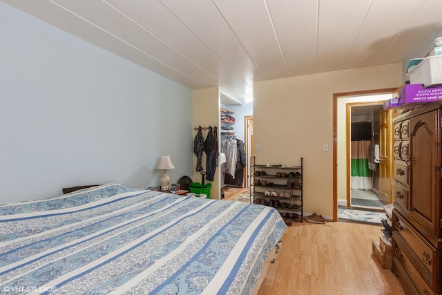 bedroom featuring light wood-style floors, a walk in closet, and a closet