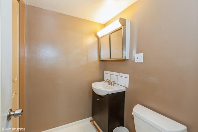 half bath with toilet, baseboards, and vanity