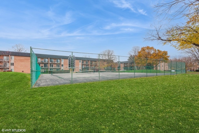 view of tennis court with fence and a yard