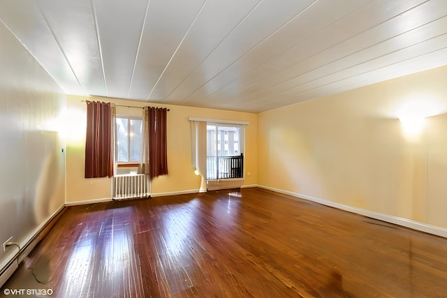 spare room featuring baseboards, a baseboard radiator, hardwood / wood-style flooring, and radiator