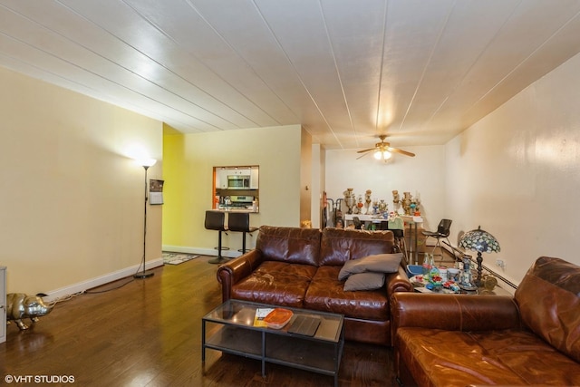 living area featuring a ceiling fan, baseboards, and wood finished floors