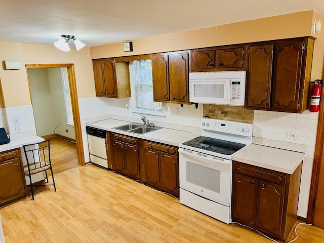 kitchen featuring decorative backsplash, white appliances, light hardwood / wood-style floors, and sink