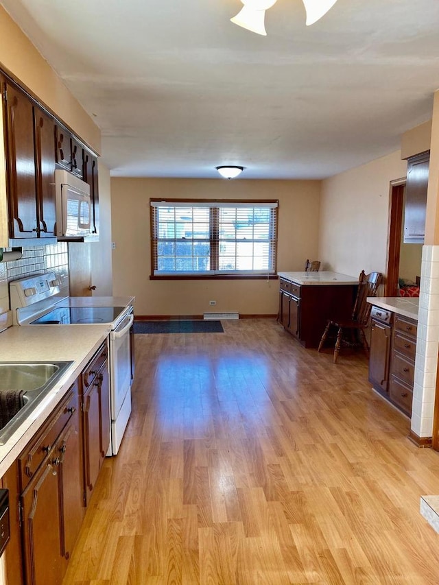 kitchen featuring white appliances, light hardwood / wood-style floors, and tasteful backsplash