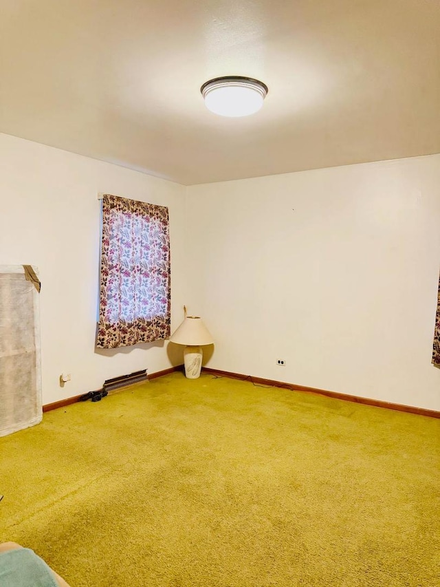 carpeted spare room with a baseboard heating unit