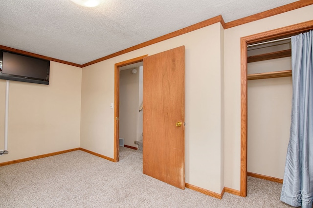 unfurnished bedroom with light carpet, a closet, a textured ceiling, and ornamental molding