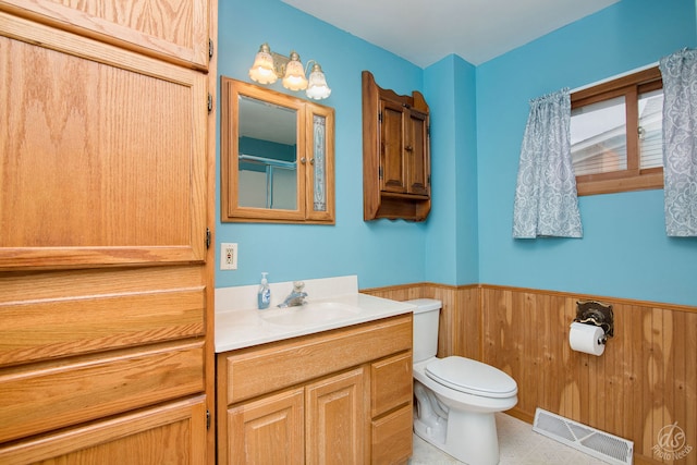 bathroom featuring tile patterned floors, vanity, toilet, and wood walls