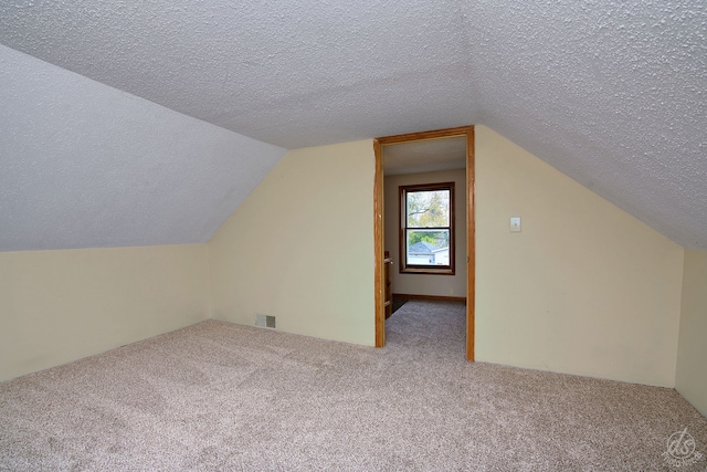 additional living space featuring carpet flooring, a textured ceiling, and vaulted ceiling