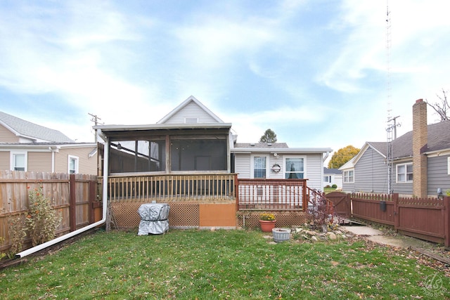 back of house featuring a yard, a deck, and a sunroom